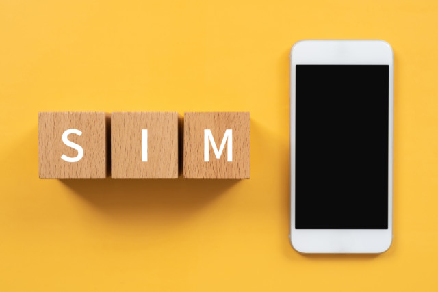 「SIM」の積み木とスマートフォン