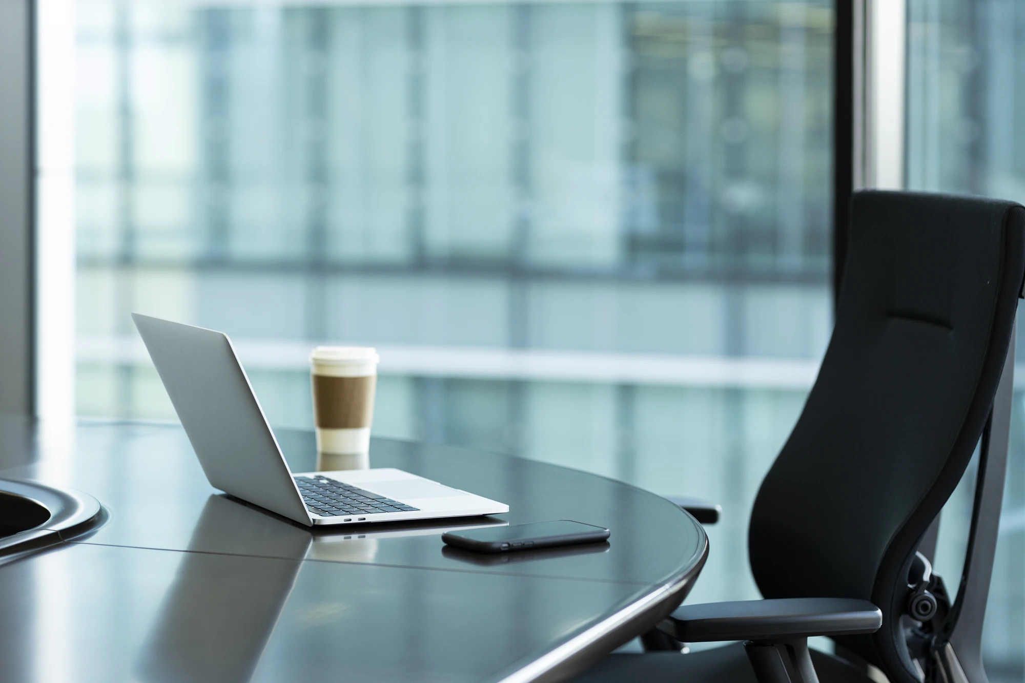 ノートPCとスマホ、ドリンクが置かれたオフィス