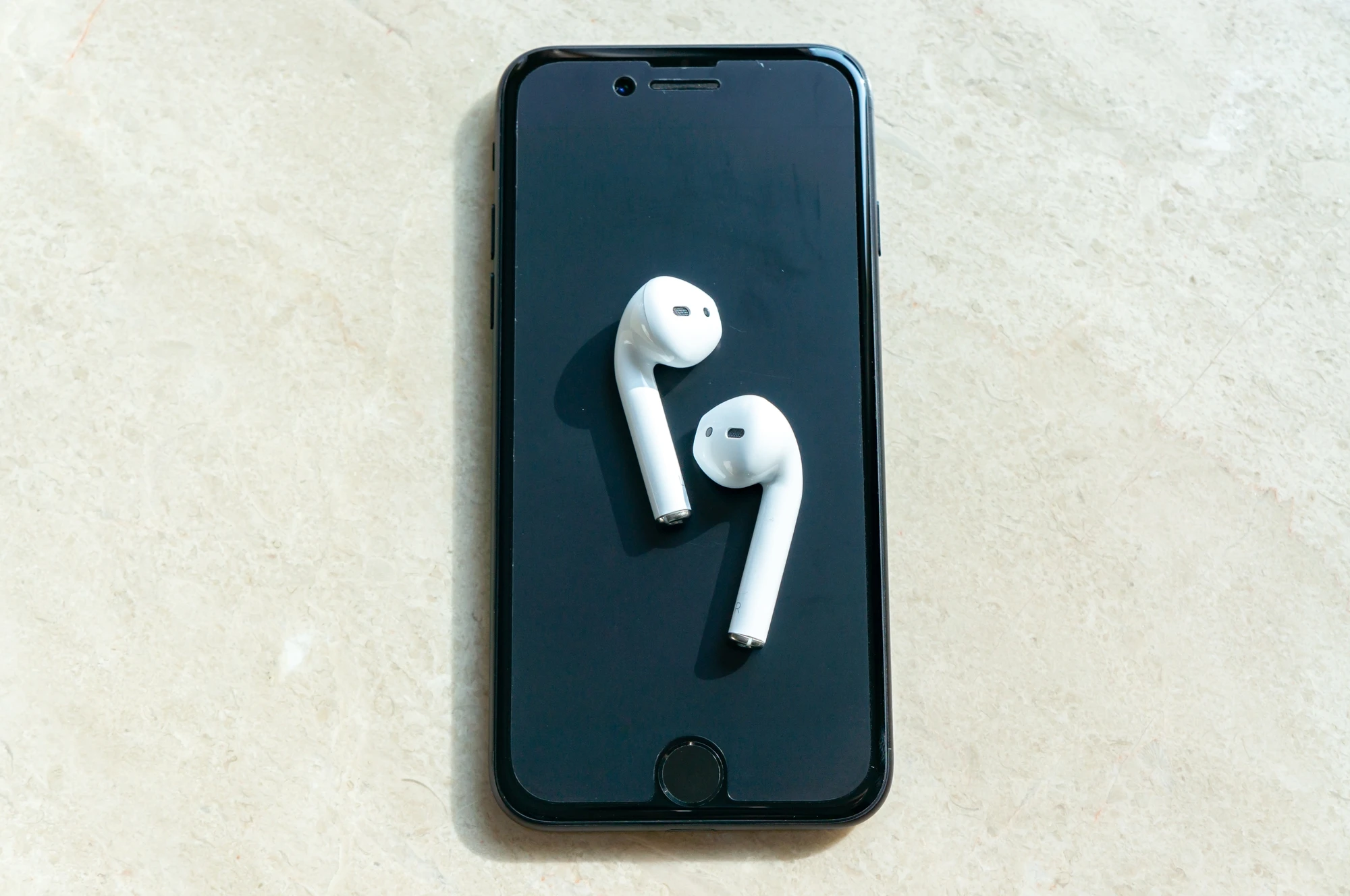 白いワイヤレスイヤホンとスマホ