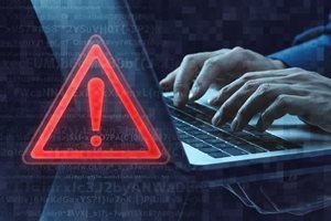 パソコンのセキュリティー警告。ノートパソコンを使う手のアップと警告マーク
