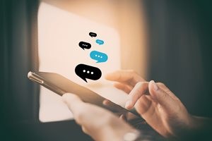 コーヒーショップの抽象的な背景でチャットアイコングラフィックを持つスマートフォンを使用する女性の手