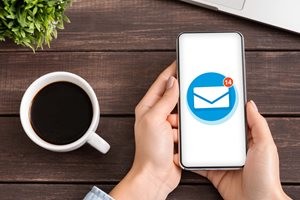 メールアプリの表示されたスマホとコーヒー