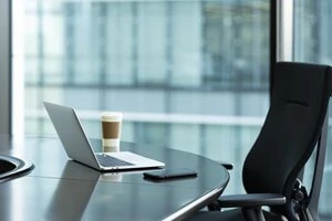 ノートPCとスマホ、ドリンクが置かれたオフィス